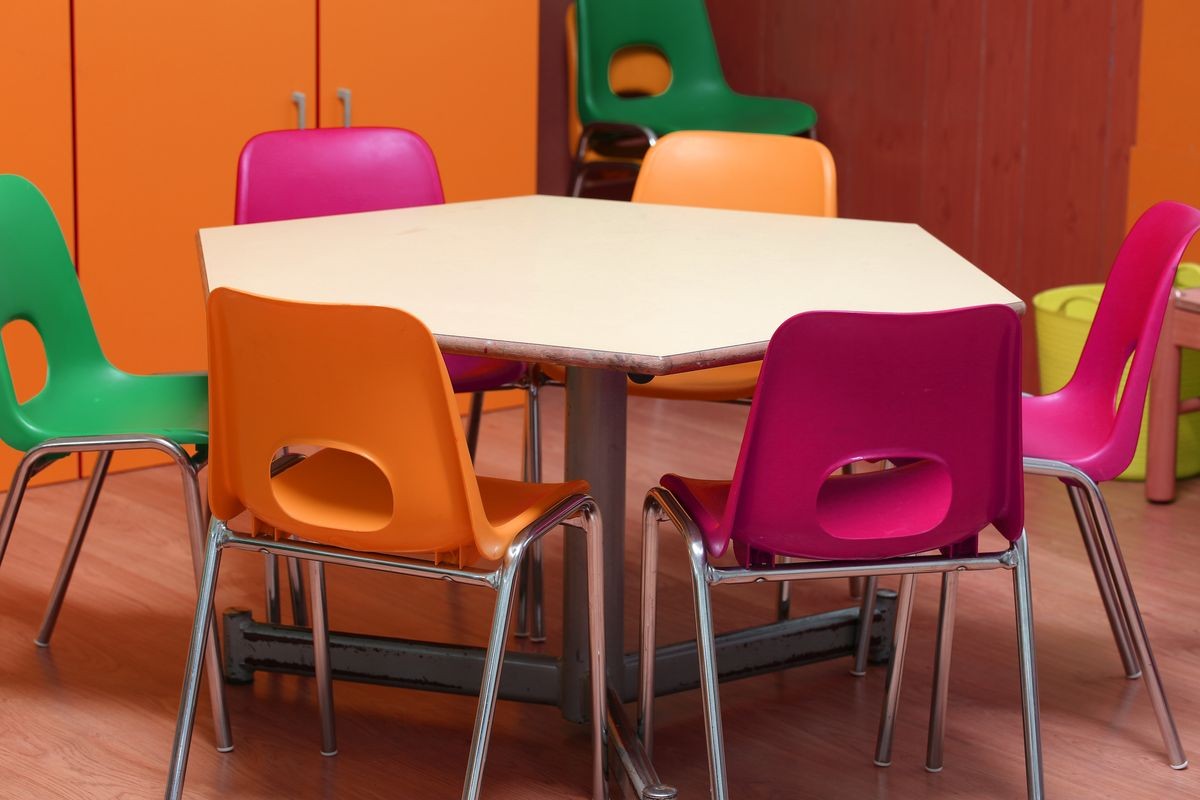 table with colored chairs in the kindergarten classroom without the children